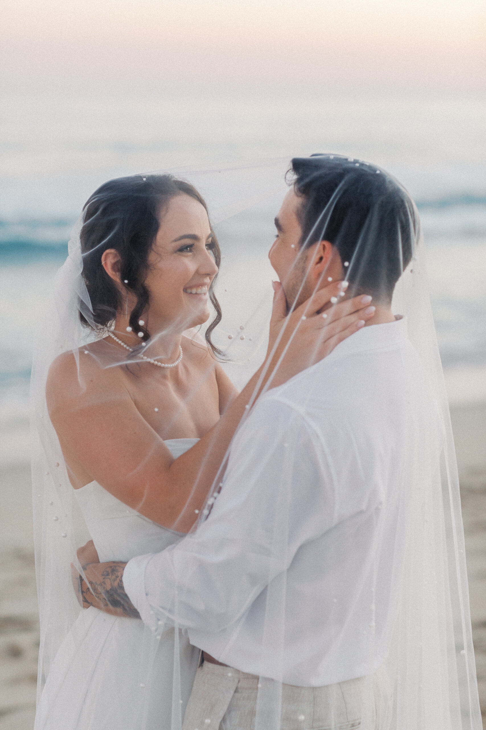 Bride and groom smiling at sunset during their Cabo San Lucas beach wedding in Mexico.