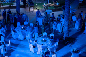 Blue-lit outdoor wedding reception at Hyatt Ziva Los Cabos with palm trees and round tables in Cabo San Lucas, Mexico.