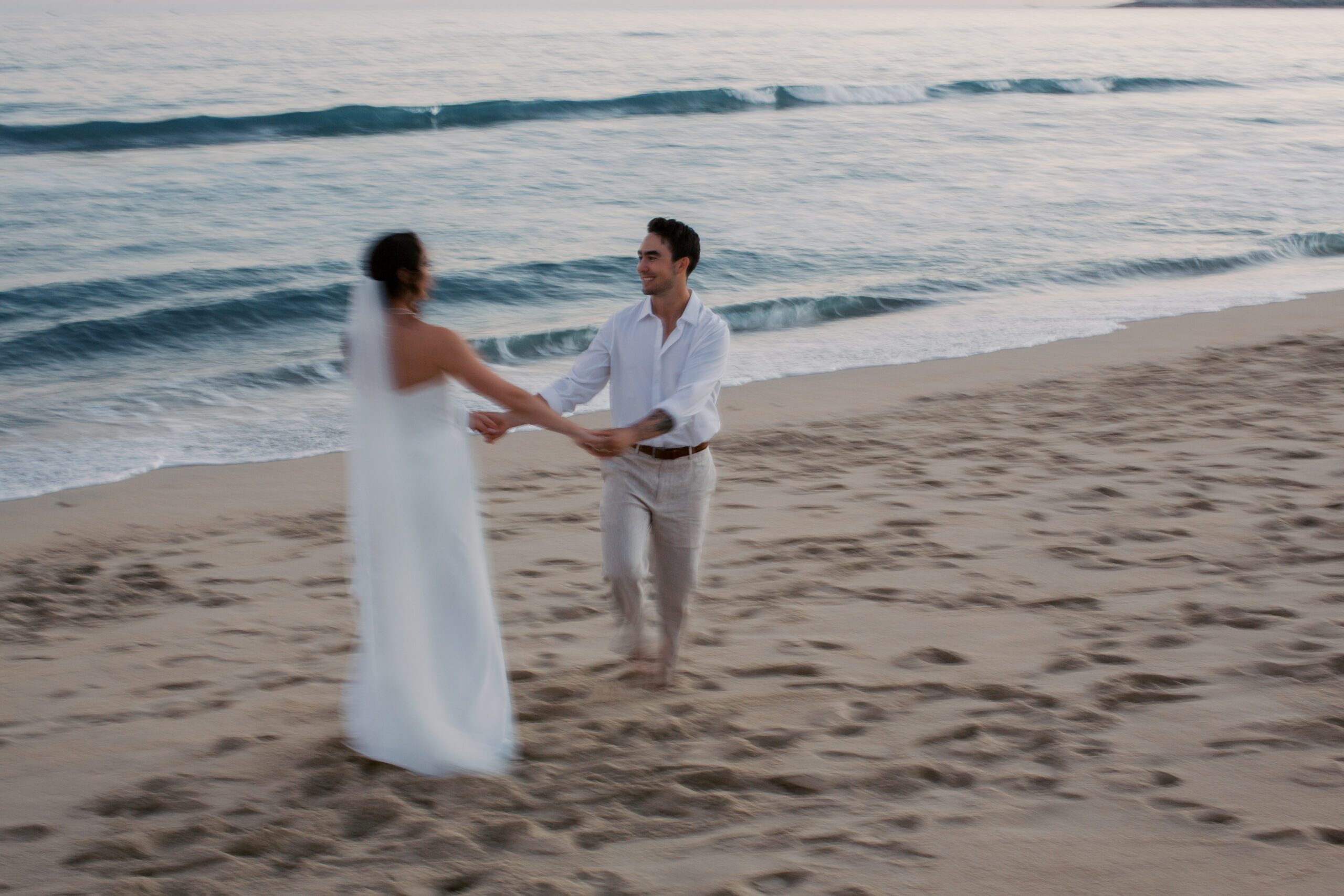 Bride and groom spinning on the beach at sunset during their destination wedding in Cabo Mexico.