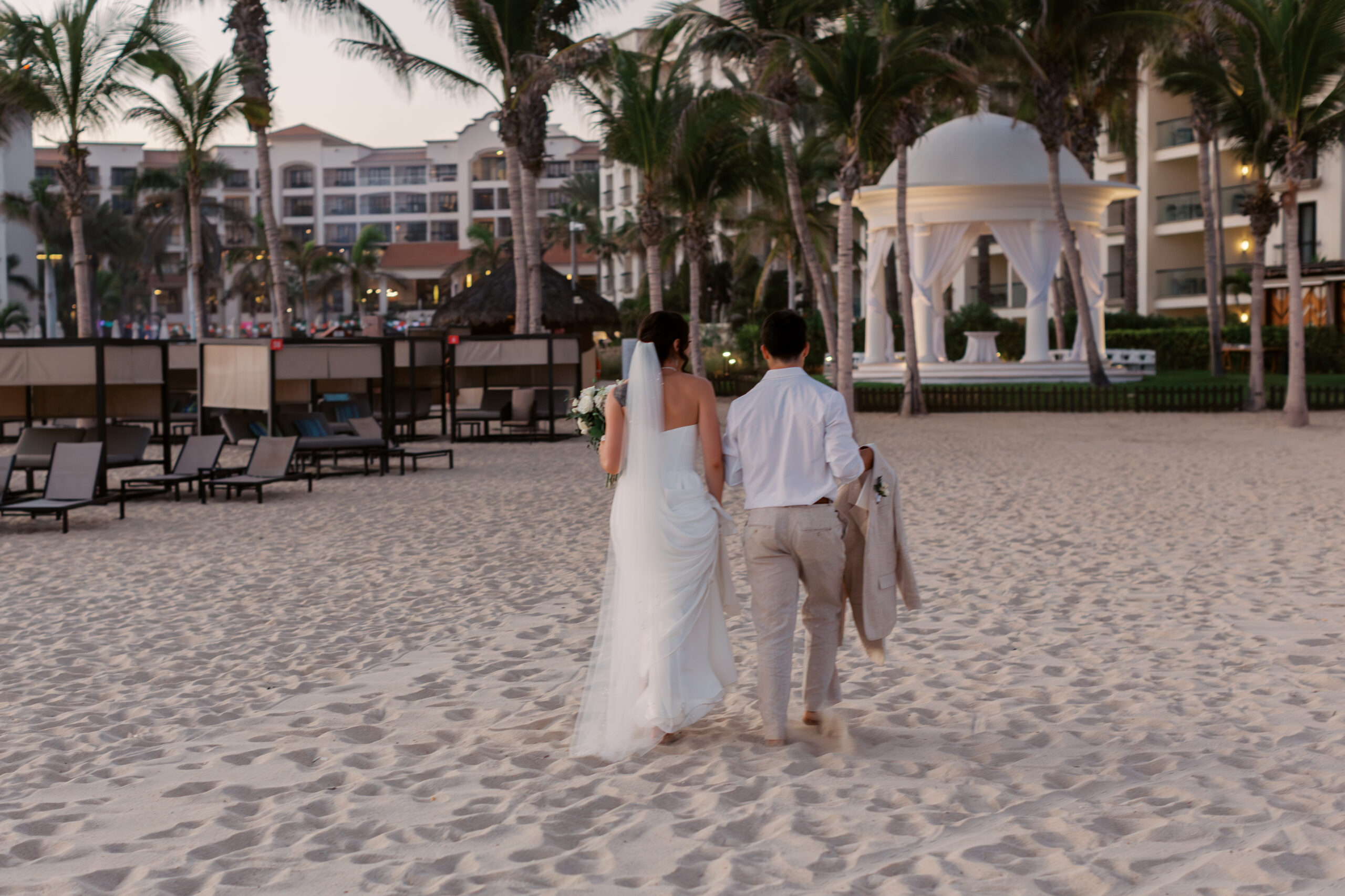 Hyatt Ziva Cabo San Lucas destination wedding couple walking on the beach toward the oceanfront gazebo ceremony location.